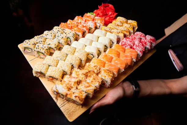 istock Waiter holding a set of sushi rolls on a plate. Close-up, selective focus. 1432810821