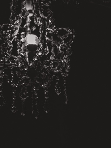 A vertical greyscale shot of the details of a gorgeous chandelier
