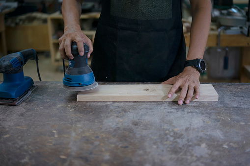 Carpenter is working in workshop. Production line for wooden furniture. Small business and craft concept.