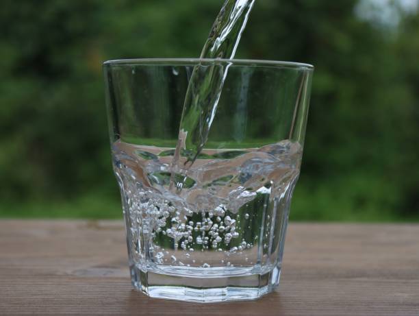 istock Transparent glass cup being filled with water, close-up 1432814301