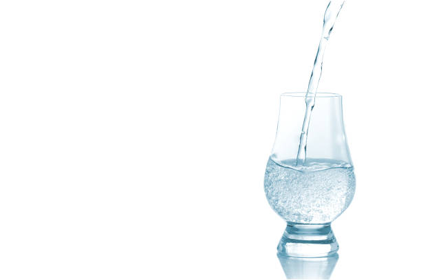 verter agua de la botella en vidrio aislado - water flowing water pouring ice fotografías e imágenes de stock