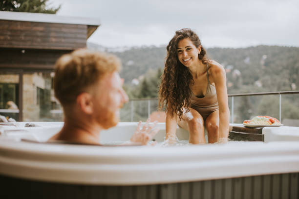 Young couple enjoying in outdoor hot tub on vacation stock photo