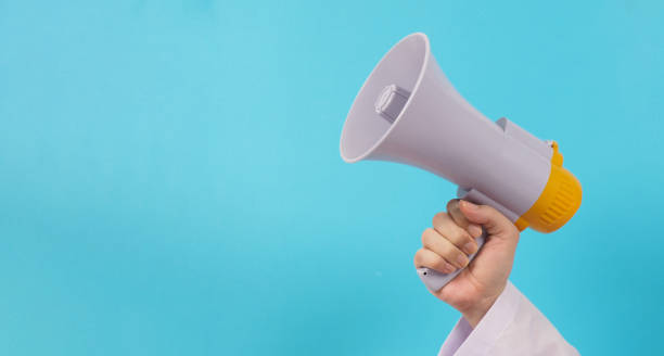 istock The doctor's hand is holding a megaphone on blue background. 1432817742