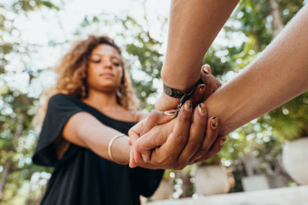 Shot of two females holding hands, diversity in skin color Women hand in hand holding each other for trust faith and hope. Two different skin tones, multiracial group anonymous activist network stock pictures, royalty-free photos & images