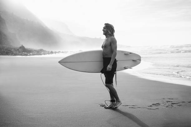 istock Young man having fun on the beach after surf session - Focus on face - Black and white editing 1432826008