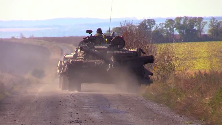 A Ukrainian tank with soldiers drives along a dirt country road. Real War 2022