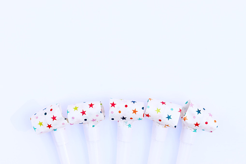 Festive pipes and horns on a white background. Congratulatory background for your text. Background for a postcard or banner for a birthday, New Year or other holiday. Noise Makers