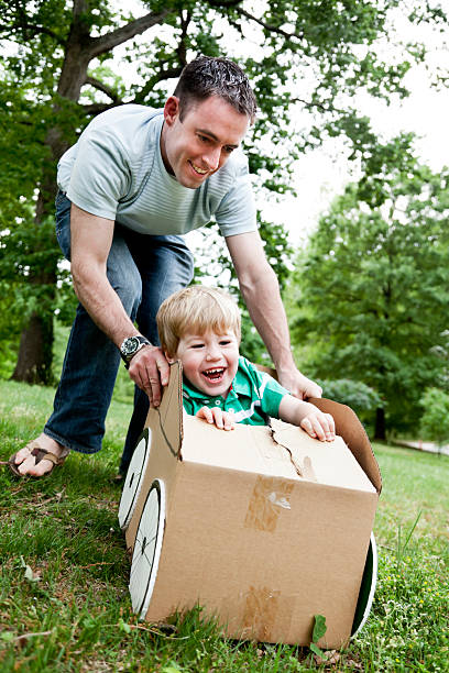 istock Little boy sitting in a cardboard car and being pushed 143283257