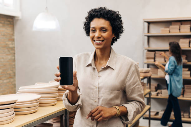 istock Happy ceramic shop owner showing a blank smartphone screen 1432832614