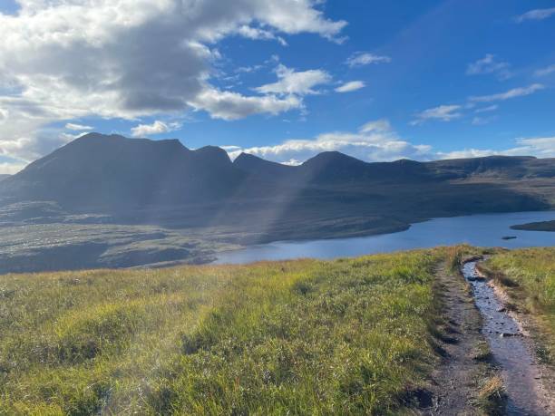 istock Gorgeous landscape with a river surrounded by green hills and trees under a cloudy sky 1432834889