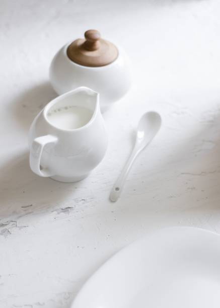 istock Small white milk jug with a spoon and sugar bowl on a marble table 1432836710