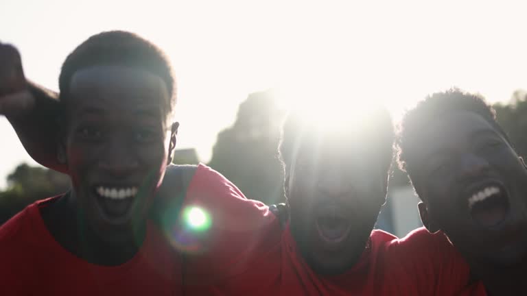 African red sport fans screaming while supporting their team - Football supporters having fun at competition event