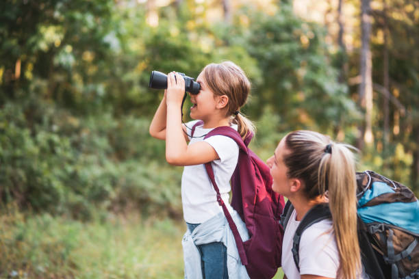 Mother and daughter using binoculars  while hiking stock photo