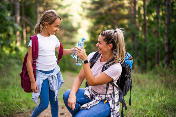 istock Mother and daughter drinking water while  hiking 1432838242