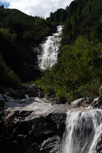 istock Vertical low-angle of a waterfall with trees and stone on both sides and sky background 1432838773