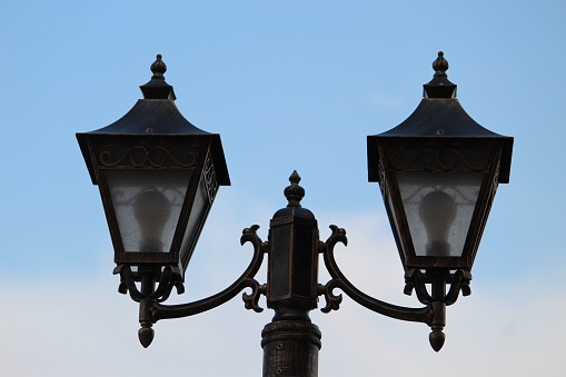 A closeup of vintage street lamps under blue sky