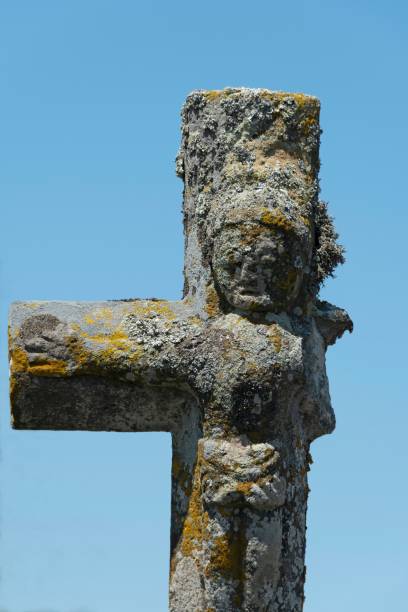 istock Vertical shot of an old stone cross with a missing arm in a blue sky background 1432839950