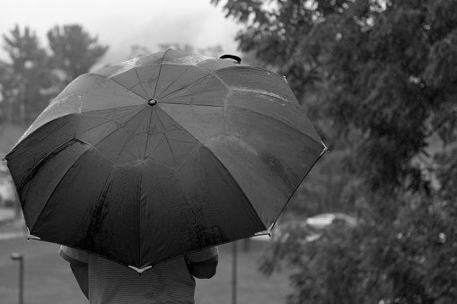 A grayscale shot of a male holding an umbrella