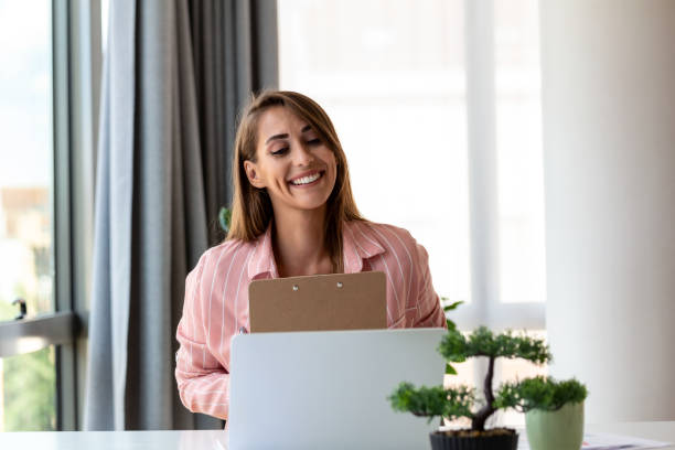 istock Focused business woman using laptop at home, looking at screen, chatting, reading or writing email, sitting on couch, female student doing homework, working on research project online 1432842559