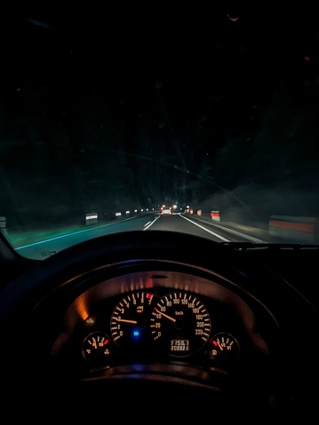 A vertical shot of the speedometer of a car driving on a highway at night