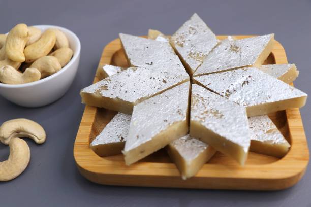 istock Kaju Katli is a traditional Indian Diamond shaped sweet or Mithai made using cashew paste, sugar, and mava or Khoya. served in a wooden plate over dark background. cashew barfi. Copy space 1432847966