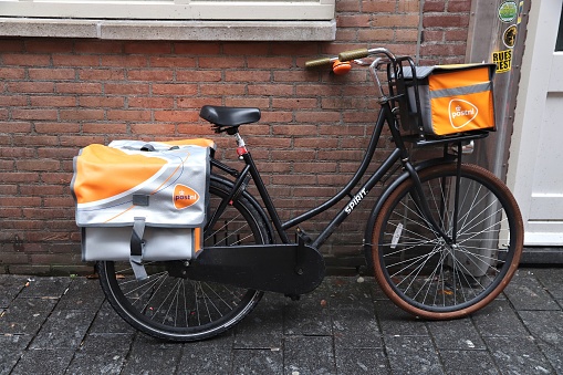 Mailman bicycle parked in Amsterdam. Mail delivery by Post NL national postal service.