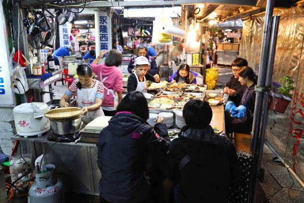Vendors prepare food at Miaokou Night Market in Keelung, Taiwan. Night markets are essential part of Taiwanese food culture.