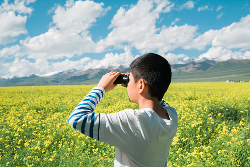 Young boy enjoying oilseed rape fields with binoculars