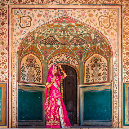 Young Indian woman, wearing sari, is going up the way to Amber Fort near Jaipur, Rajasthan.  Amber Fort is located 13km from Jaipur, Rajasthan state, India. It was the ancient citadel of the ruling Kachhawa clan of Amber, before the capital was shifted to present day Jaipur.