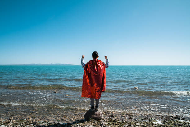 Young superman showing muscles towards lake