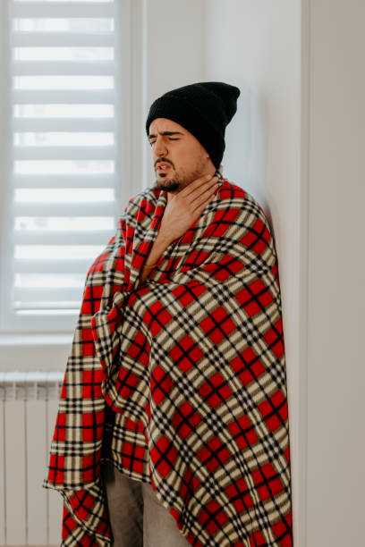 istock Man freezing in living room and touching his neck 1432854525