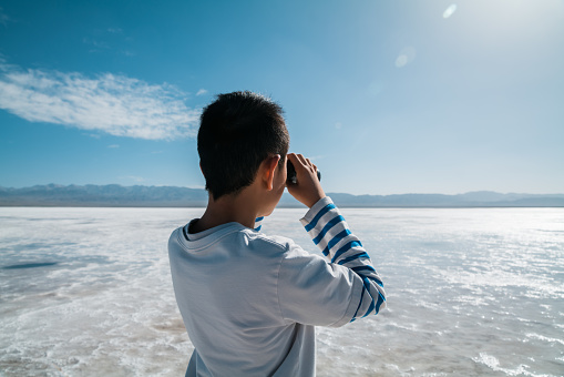 Young boy enjoying salt lake with binoculars