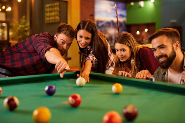 istock Group of friends having fun while playing pool in a local pool hall 1432855378