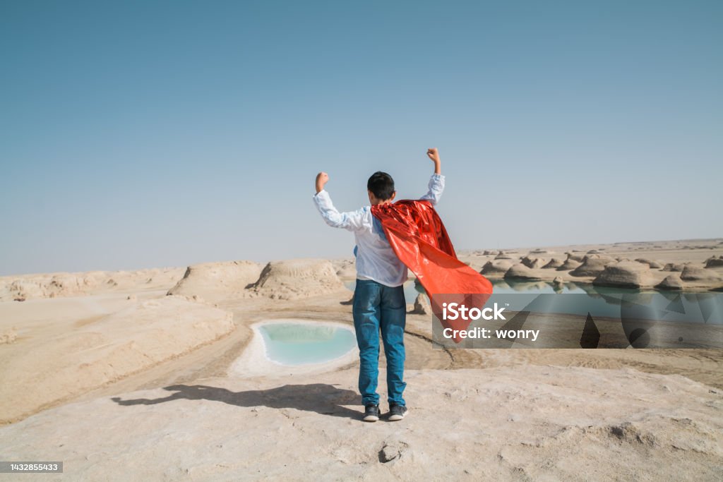Young superman showing muscles at Yardang hill 10-11 Years Stock Photo