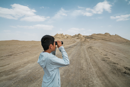 Young boy enjoying scenery with binoculars at oboliang Yardang