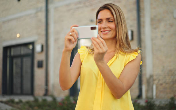 istock Beautiful woman taking pictures with her smartphone while exploring a city 1432855742
