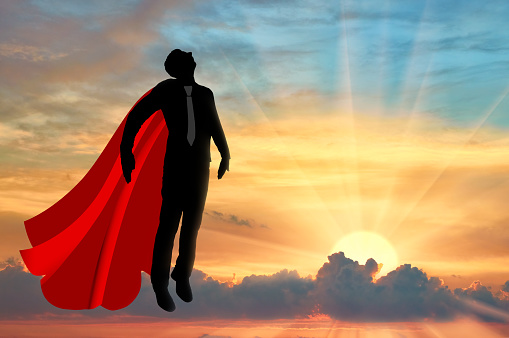 Superhero businessman superhero. Silhouette of a businessman in the image of a Superhero flies in the sky at sunset