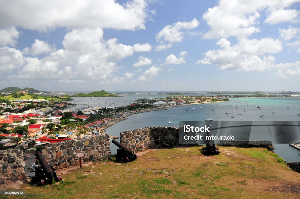 Fort Saint-Louis bastion with cannons, Marigot city and bay panorama, Saint Martin (French part) Marigot, Collectivity of Saint Martin / Collectivité de Saint-Martin, French Caribbean: bastion with old French cannons at Fort Saint-Louis, built during the reign of King Louis XVI, wealthy Marigot was a frequent target for looters and buccaneers from Anguilla - panoramic view over the town, Marigot and Nettlé bays, Sandy Ground isthmus and in the background Simpson Bay lagoon. Marigot Stock Photo