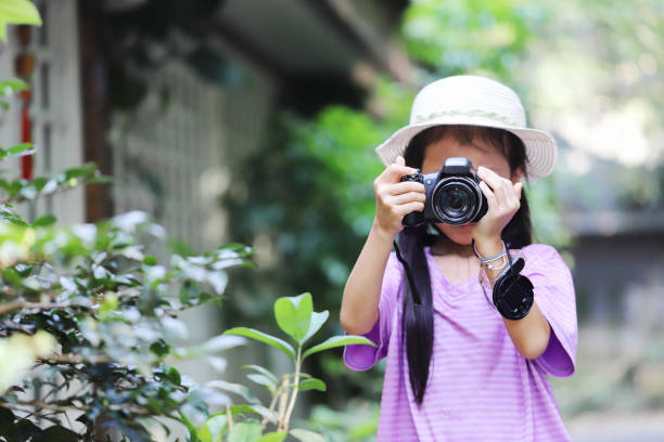 a smiling Asian girl take photos with a digital camera in a forest.
