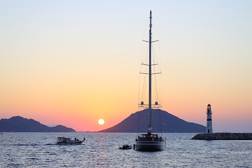 Bodrum, Turkey. 14 August 2022: Seascape at sunshine. Lighthouse and sailings on the coast. Seaside town of Turgutreis and spectacular sunshine