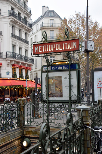 Metropolitain station entrance with typical sign, in a Paris street, in Autumn.