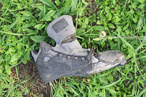 A man is repairing old shoes, although he is not wearing any.