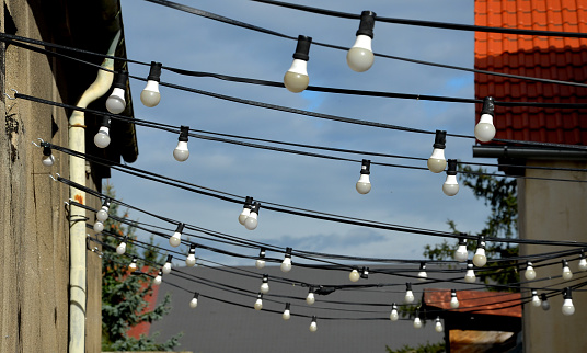 Front shot of light bulbs hanging from cable against back yard during night