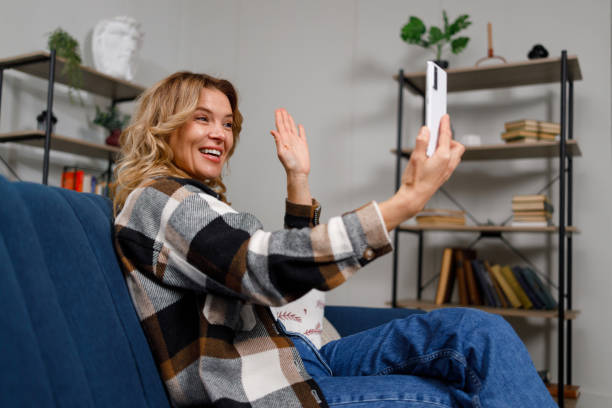 istock Mature woman waving hand during video call on smartphone while sitting on sofa 1432874149