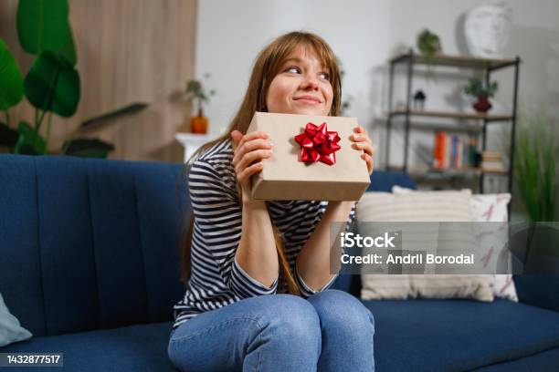 Girl With Gift Box Sitting On Sofa At Home Stock Photo - Download Image Now - Gift, One Woman Only, Only Women