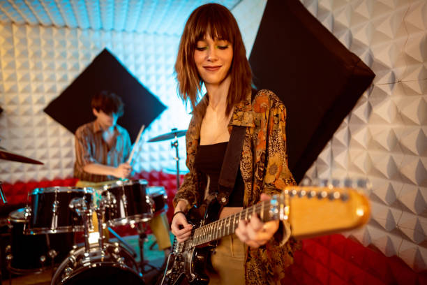 istock Female guitar player and male drummer, having rehearsal at music studio 1432881175