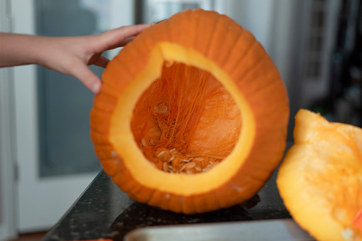 Child's hand hollowing out a pumpkin to carve in the Autumn