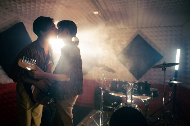 Male and female musicians kissing during rehearsal at the music studio Young Caucasian male and female musicians kissing during rehearsal at the music studio kiss entertainment group stock pictures, royalty-free photos & images