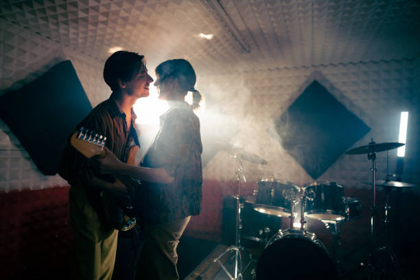 Male and female musicians kissing during rehearsal at the music studio Young Caucasian male and female musicians kissing during rehearsal at the music studio kiss entertainment group stock pictures, royalty-free photos & images