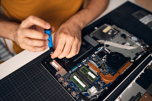 High angle view of unrecognizable Caucasian man with screwdriver repairing his laptop